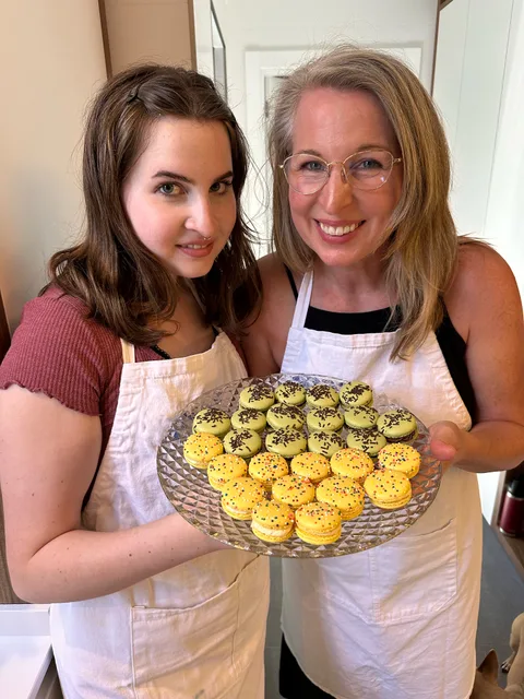 Ellie and a student holding a tray of freshly made macarons